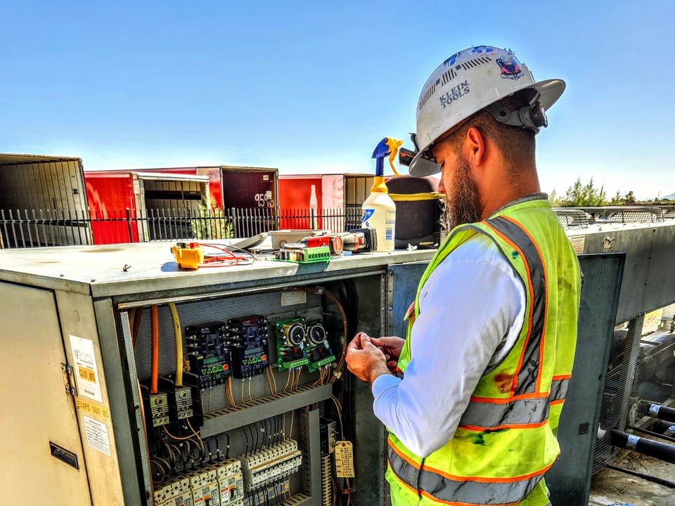 American Cool technician inspecting the electrical controls of rooftop refrigeration equipment
