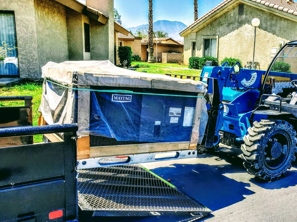 Packaged residential HVAC unit being moved into place with a forklift