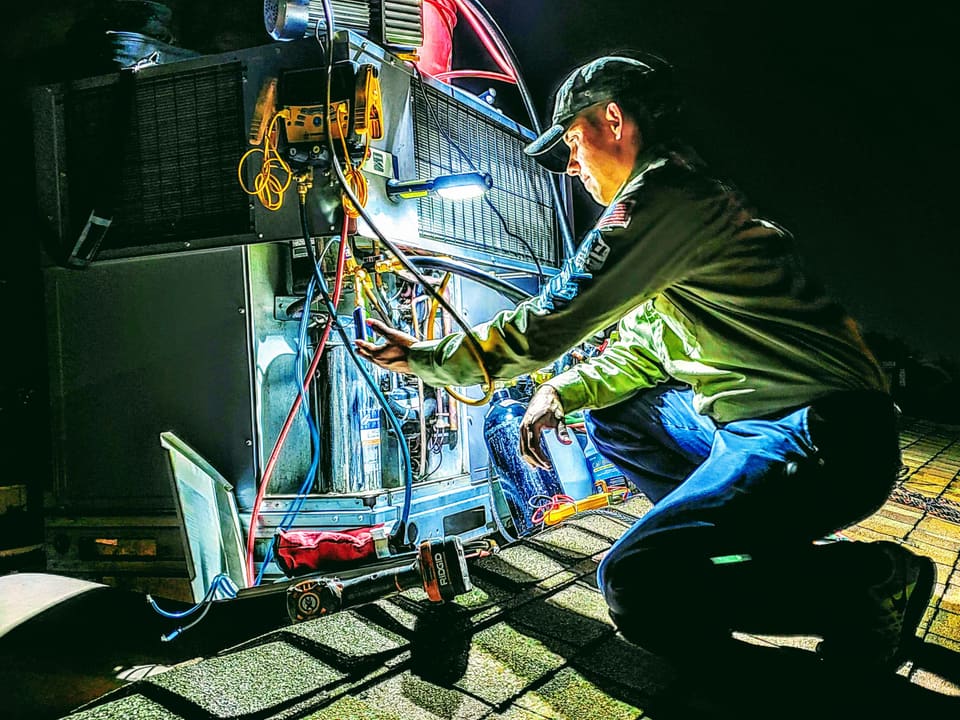 American Cool technician diagnosing a residential outdoor HVAC unit with digital gauges