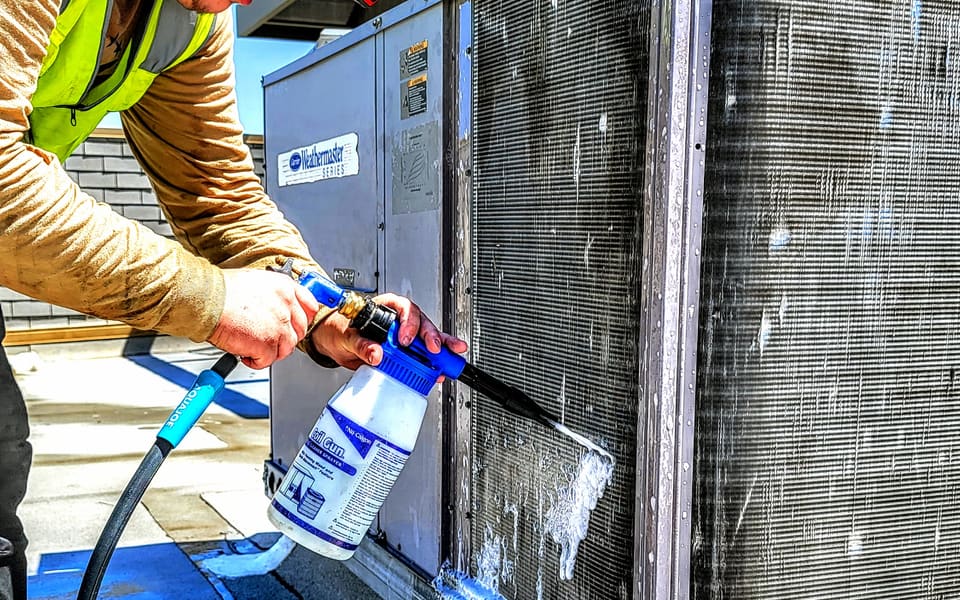 American Cool technician cleaning a commercial HVAC condenser coil
