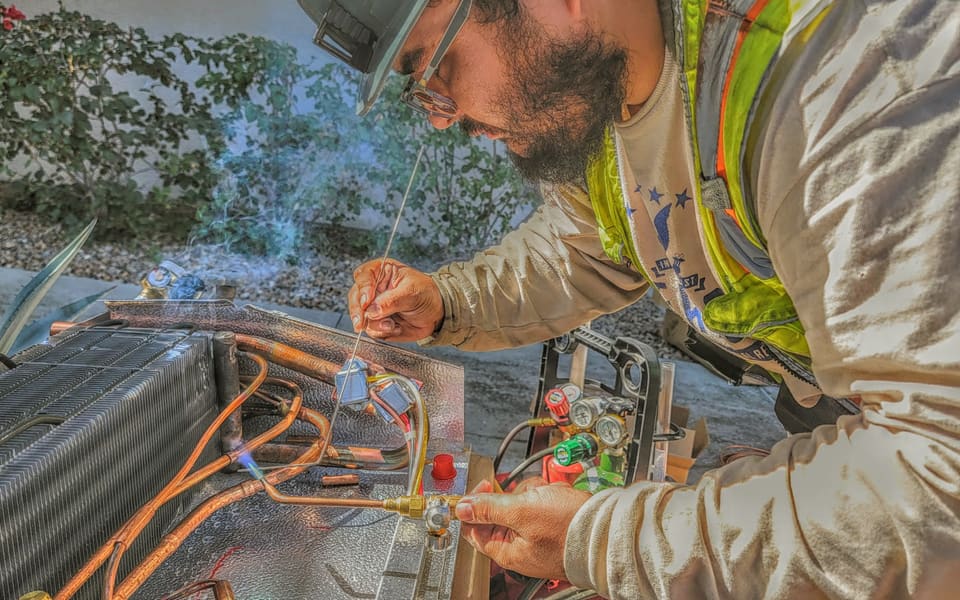 American Cool technician brazing copper tubing during a commercial equipment repair